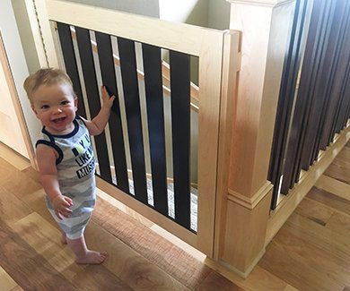 Baby standing by Gatekeepers child safety gate for stairs