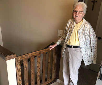 Elderly woman standing by staircase gate