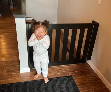 Little girl laughing near child safety gate