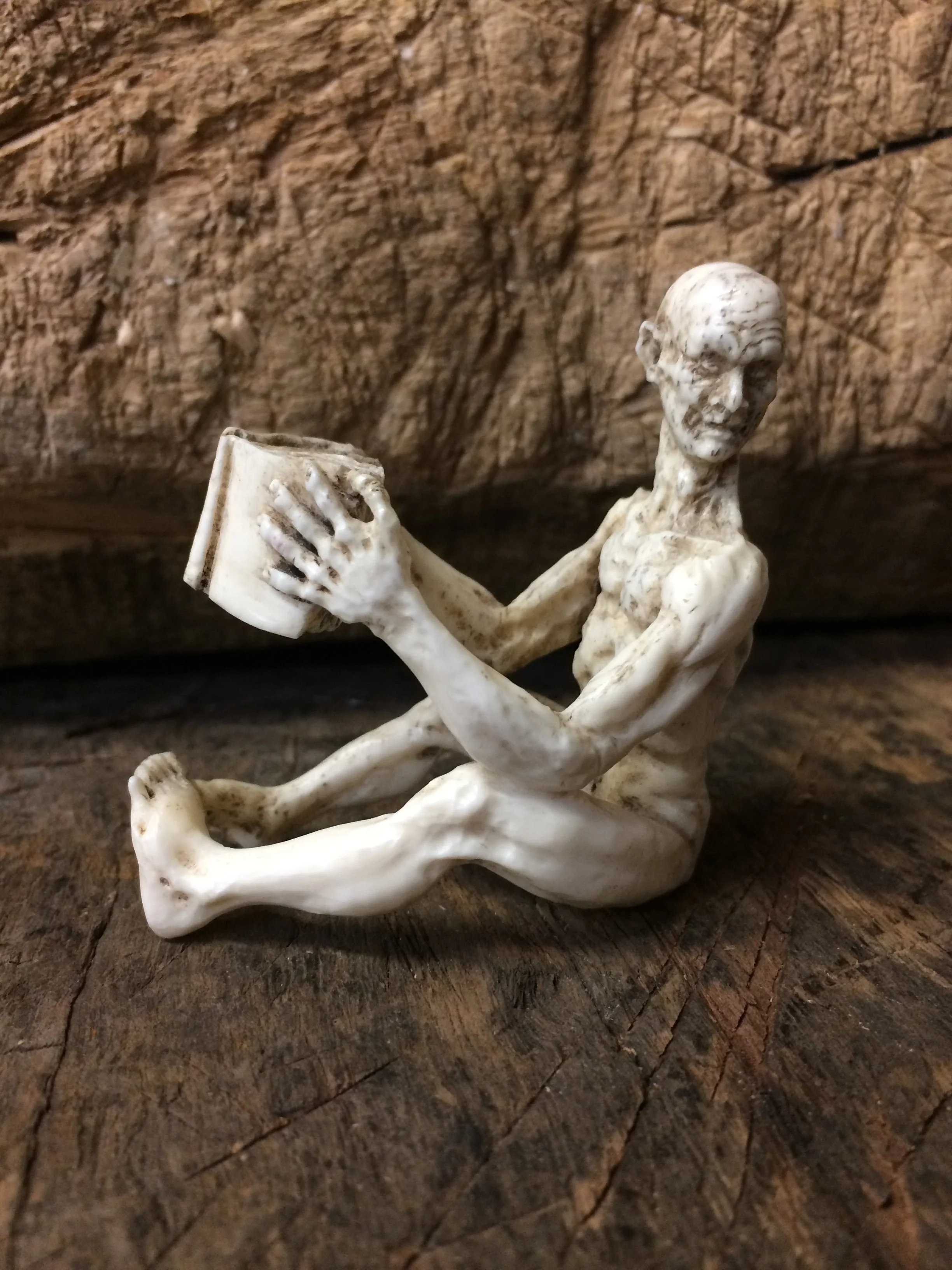 A miniature carved in the round bone naked figure looking up from his book. Fully three dimensional. The Scholar by Jason Thomson