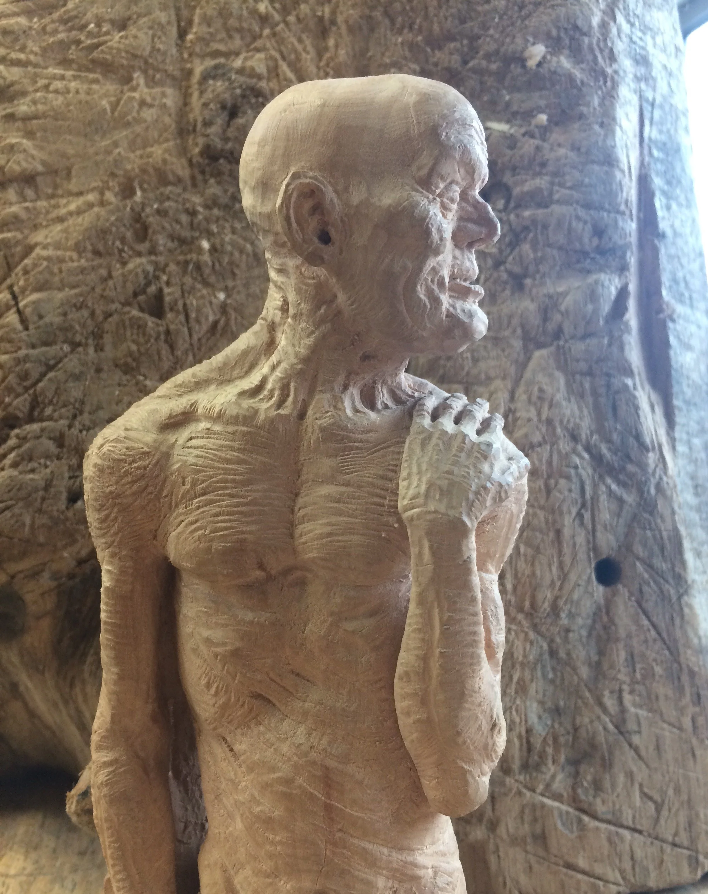 Sawpoint by Jason Thomson carved in crabapple wood this miniature sculpture has a wood saw behind his back and emerges submerges into out of the surface