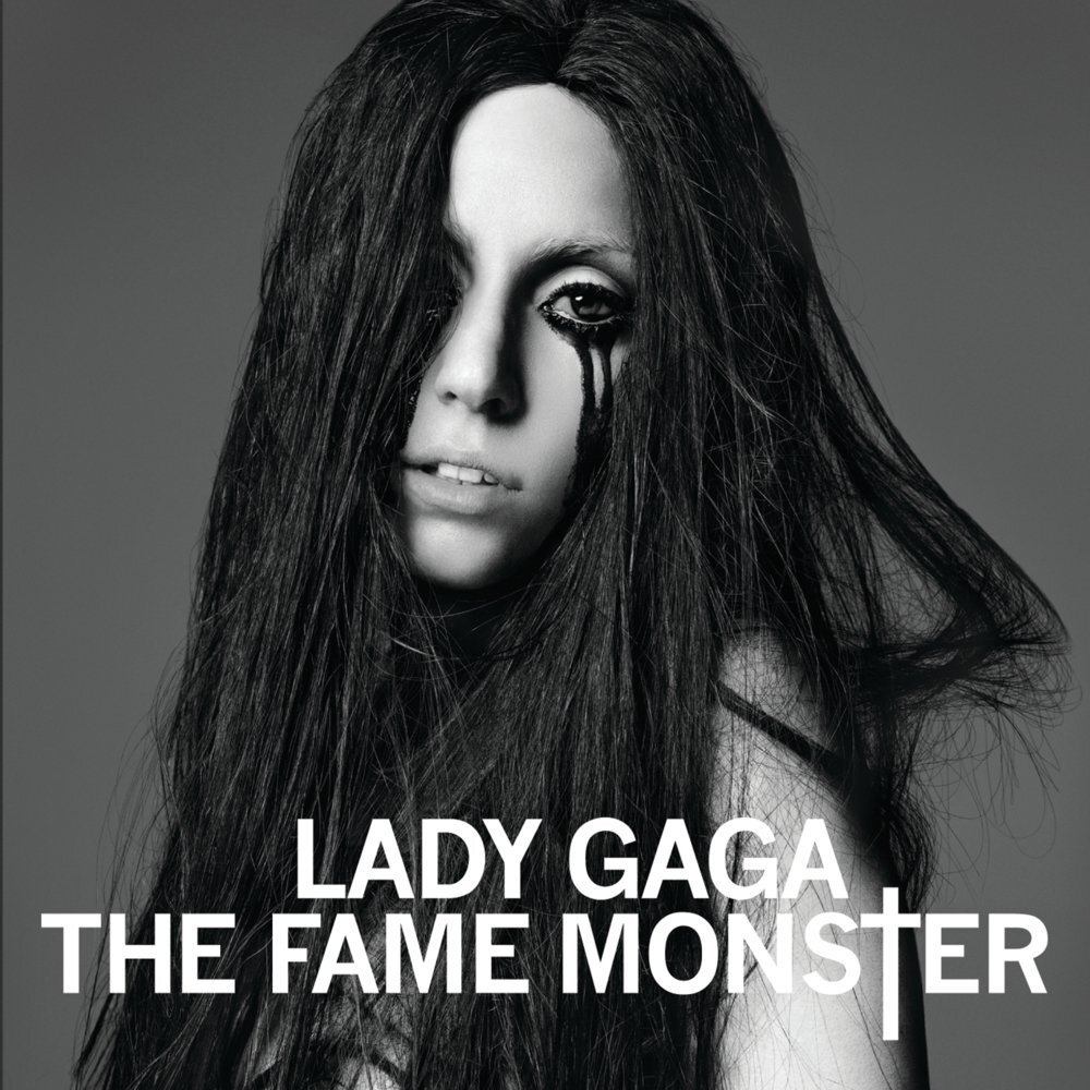 Album Artwork for Lady Gaga's Album "The Fame Monster." The photo is black and white grayscale featuring Gaga in a long black wig, looking over her shoulder with black liquid pouring from her undereyes.