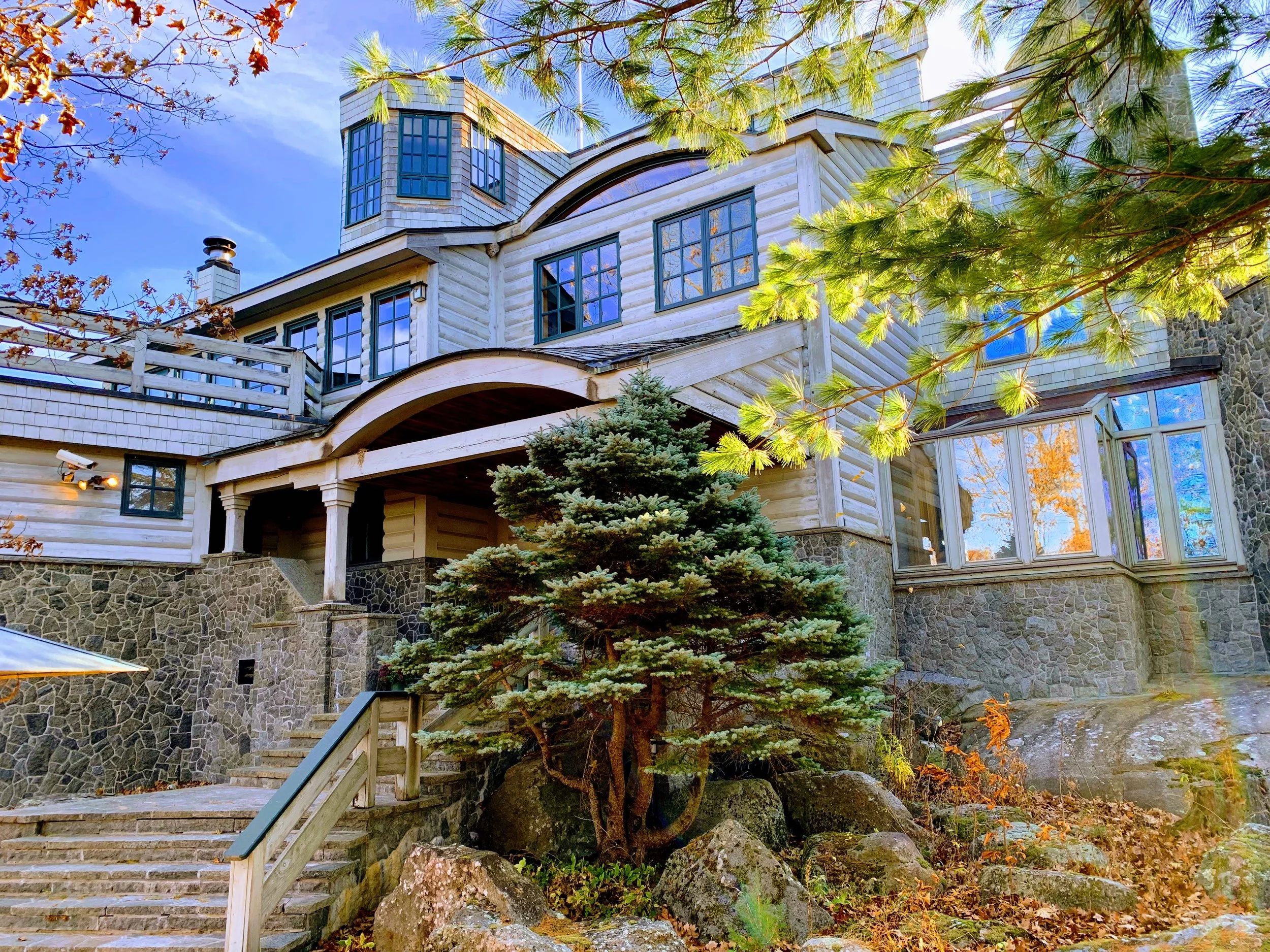 Large stone and wood mountain house surrounded by trees and stunning adirondack views