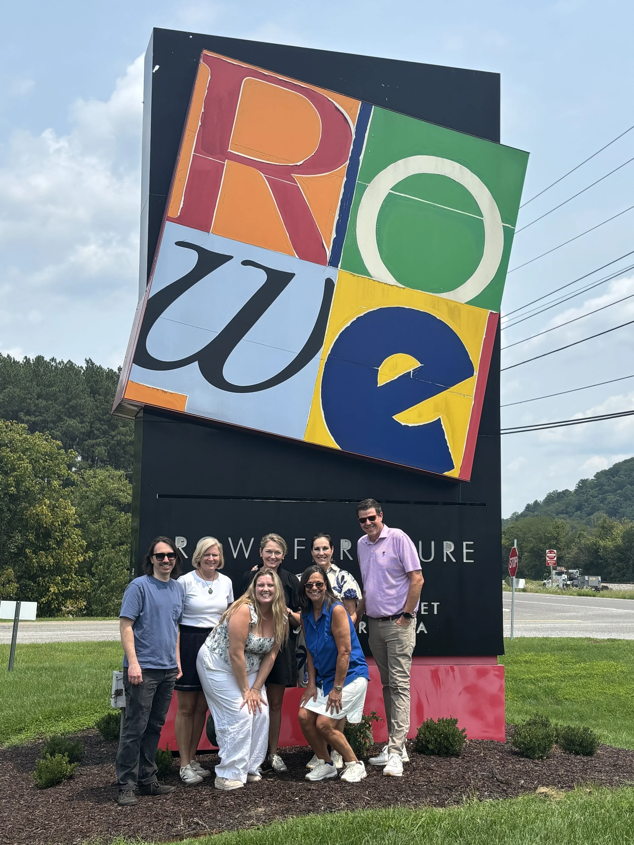 Group photo of the Curated Furnishings team standing in front of the Rowe Furniture factory sign during a tour of the Salem, Virginia manufacturing facility.