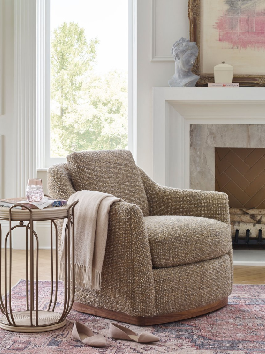 The Remy Swivel Chair is pictured in a styled living room setting, draped with a blanket for a comfortable, cozy feel.