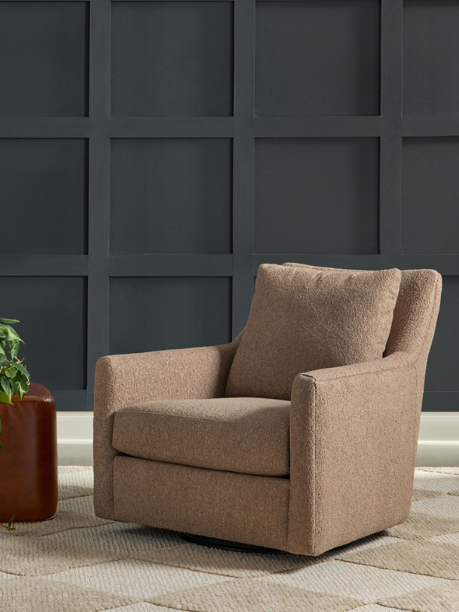 Styled view of the Wylie Swivel Chair, pictured in neutral fabric with a leather ottoman. Both pieces are in shown in front of a color drenched blue wall.