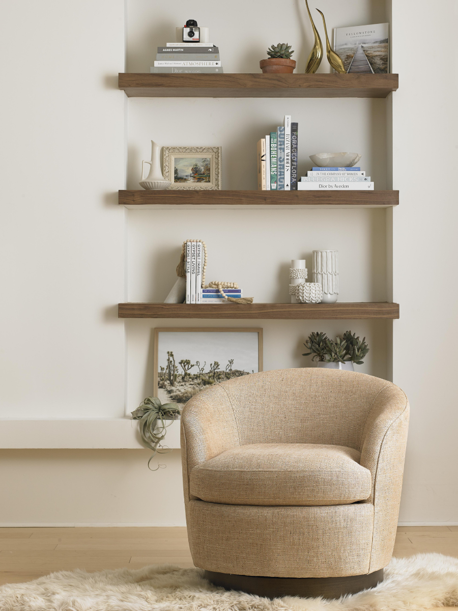 Styled view of the Claudia swivel in a living room, with bookshelves behind.