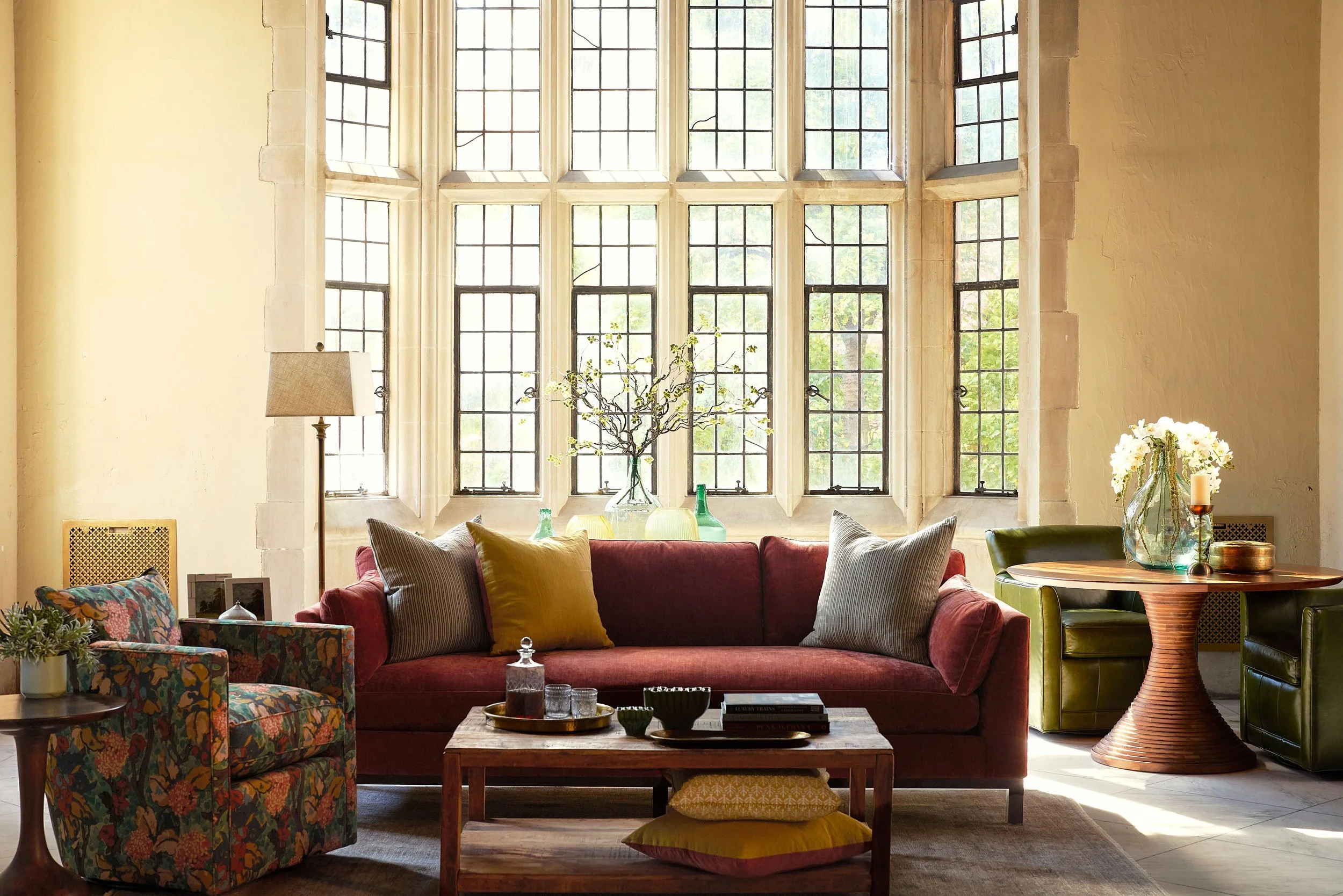 A living room scene with a sofa, chair, coffee table and dining room furniture from Curated Furnishings. The room is styled at the Branch Museum in Richmond, Virginia.