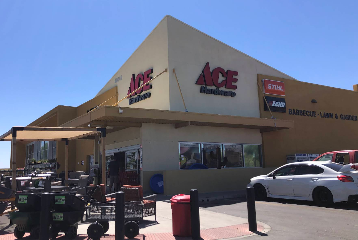 Exterior of an Ace Hardware store with shopping carts, parking lot, and clear blue sky.