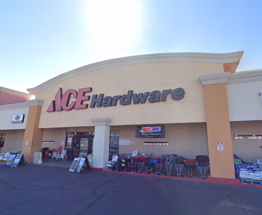 Front entrance of an ACE Hardware store with outdoor display of tools and supplies, under clear blue sky.
