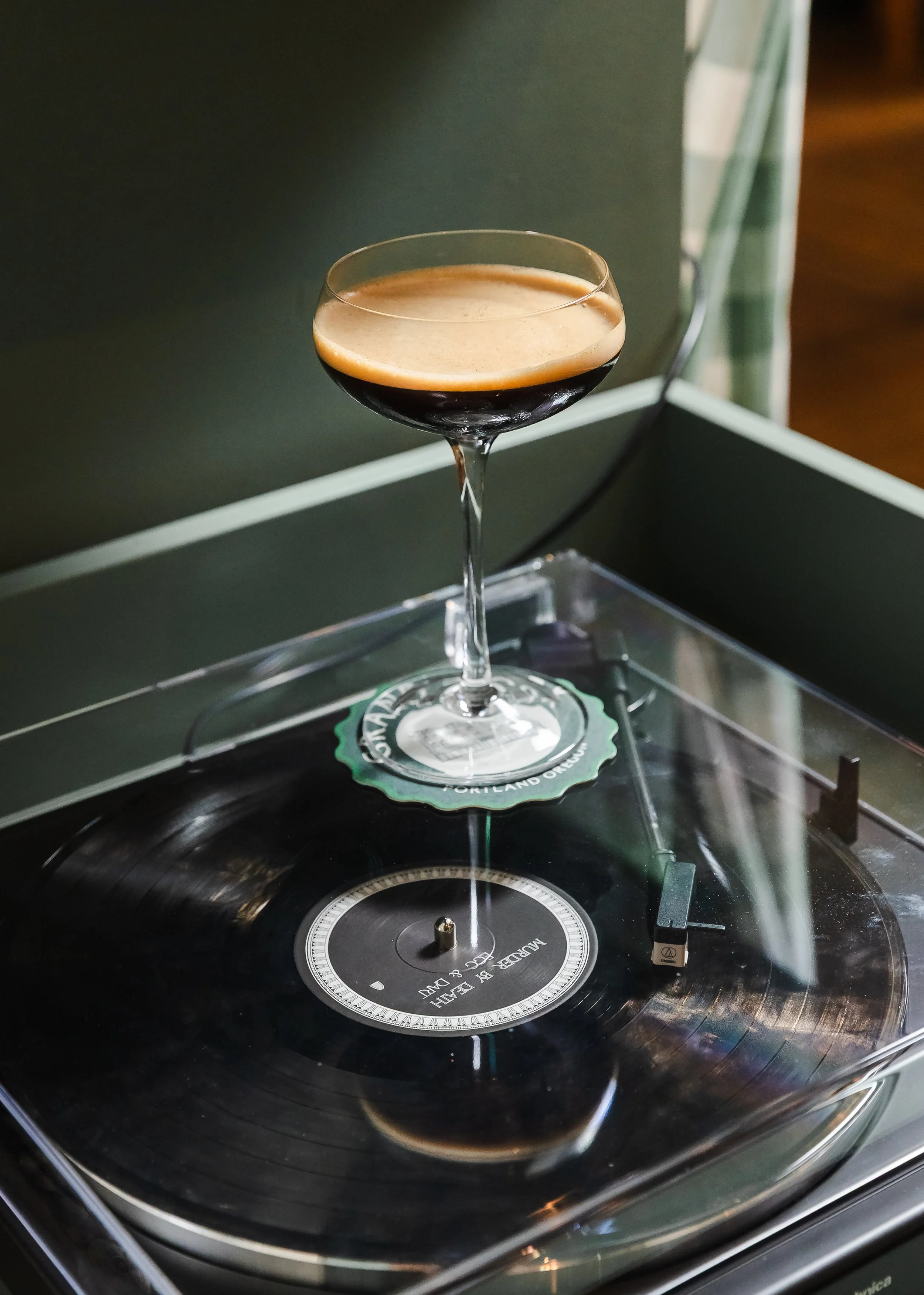 Espresso martini in a coupe glass resting on a vinyl record on a turntable