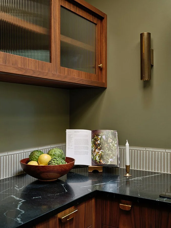 A bowl of vegetables and a cookbook in the corner nook of a kitchen. 
