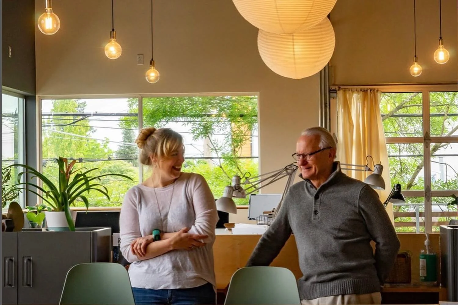 Two principal architects smiling and looking towards each other. They are in their office.