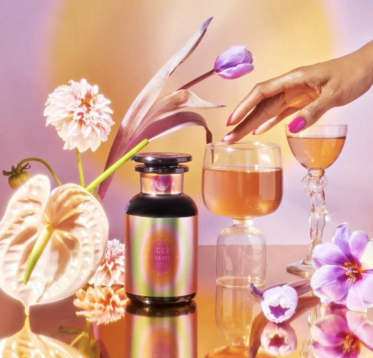 tea bottle with flowers and glassware and hand with pink nail polish