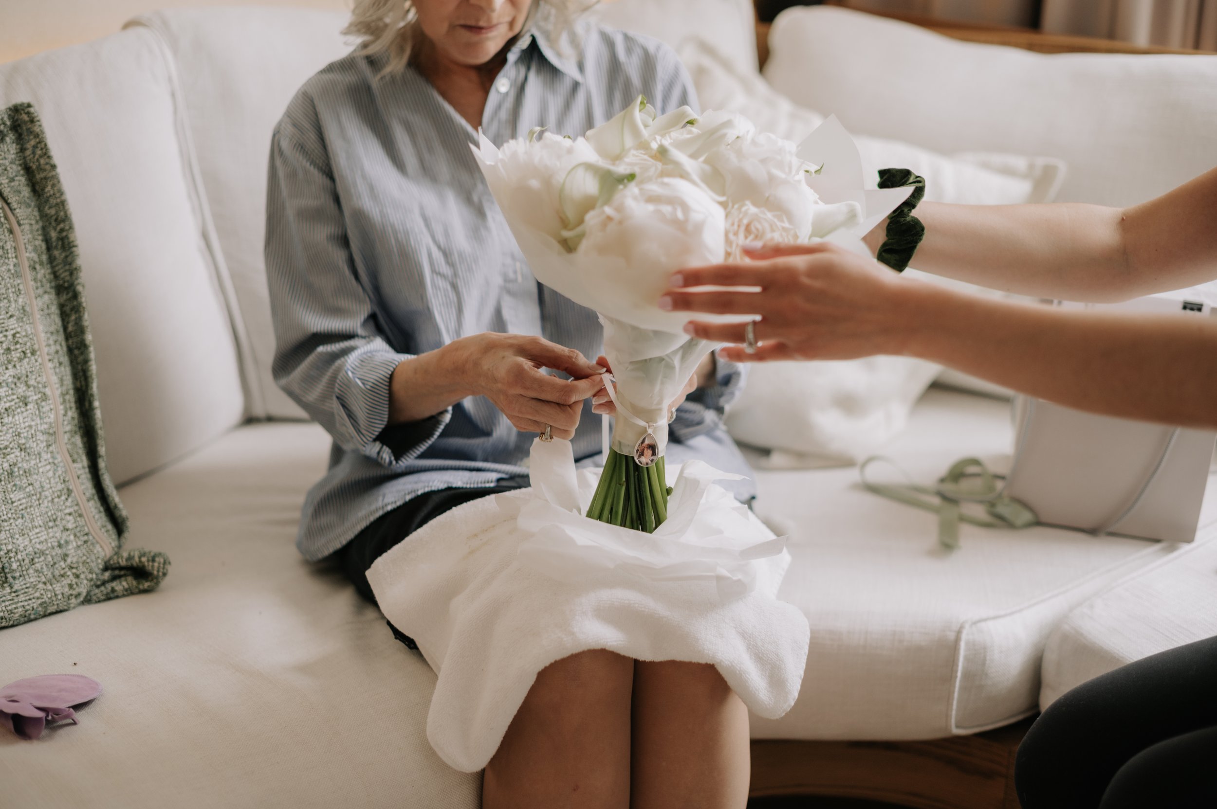 London wedding at Marylebone Town Hall step mum adding mum photo to bouquet 