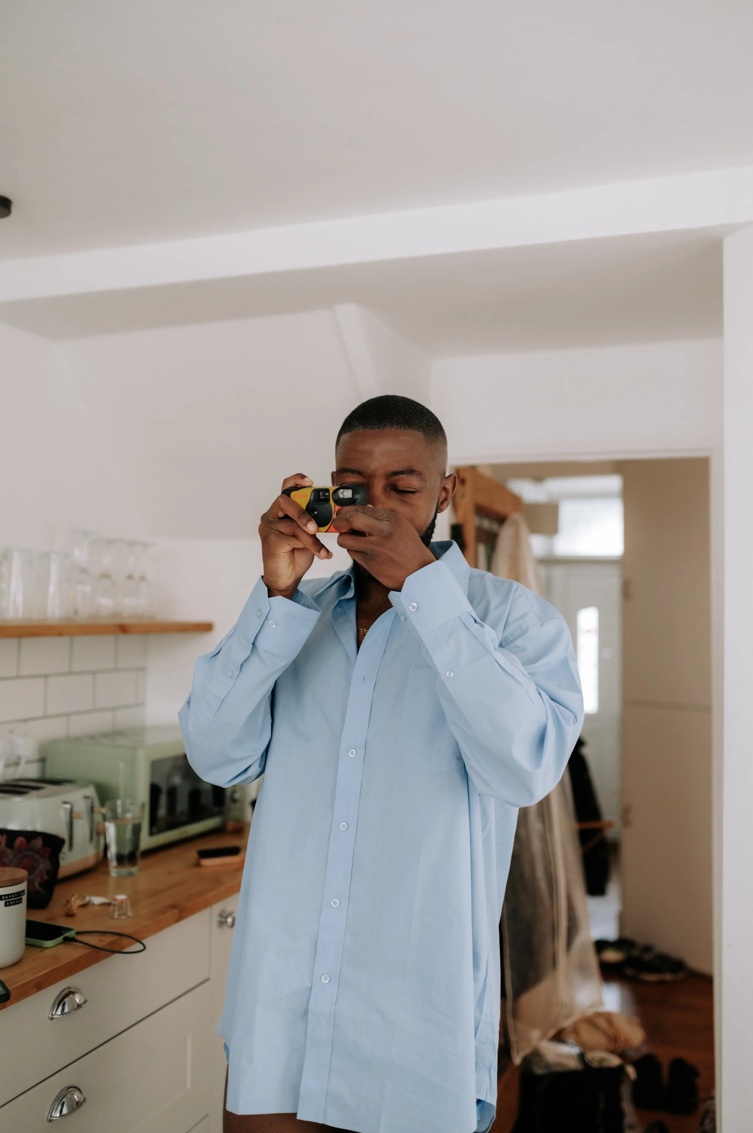 Bridesman taking disposable camera picture at Brighton wedding. Fine art documentary wedding photography.  