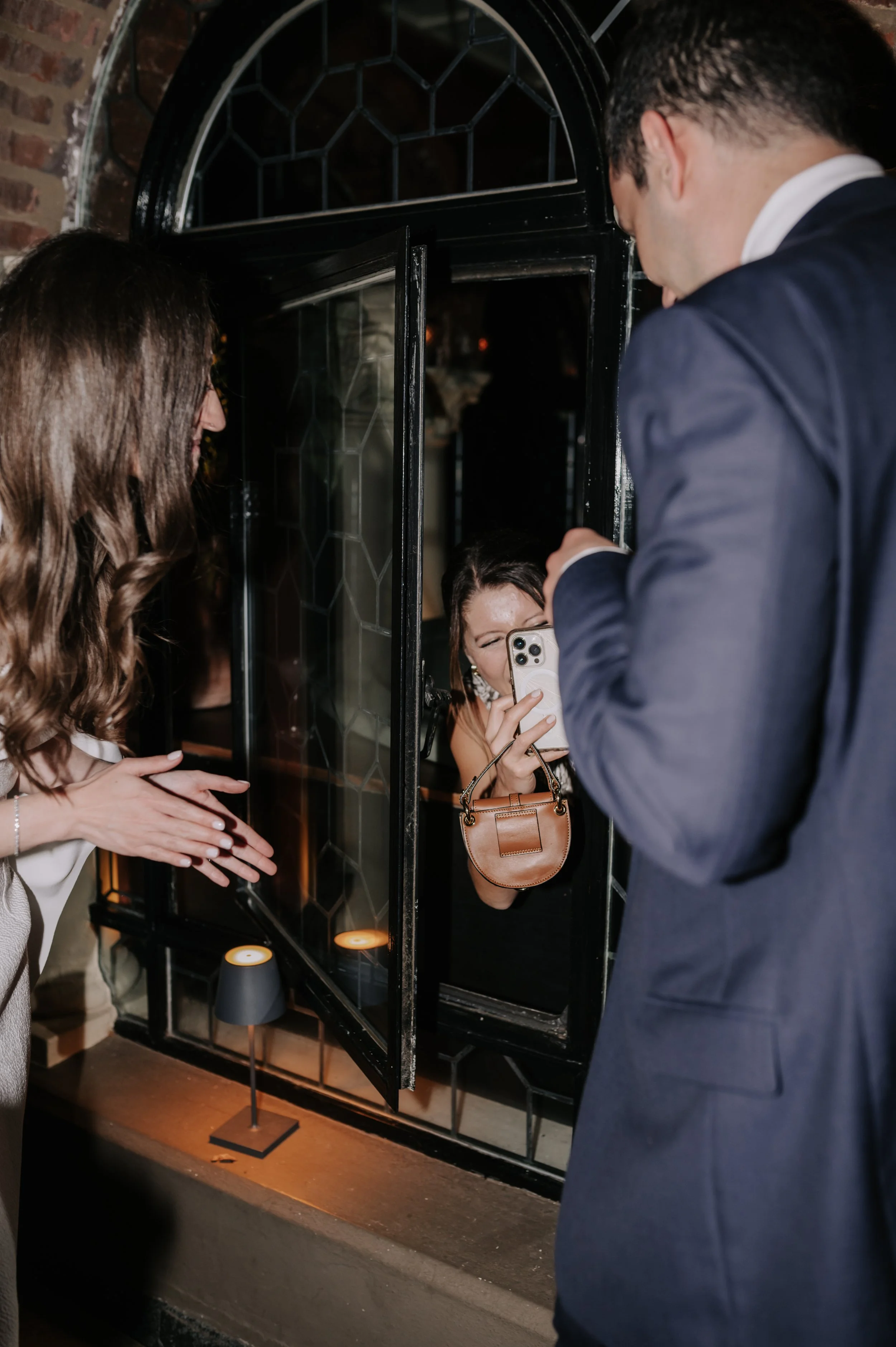 London wedding photography at Belvedere in Holland Park guest taking picture of bride and groom through window 