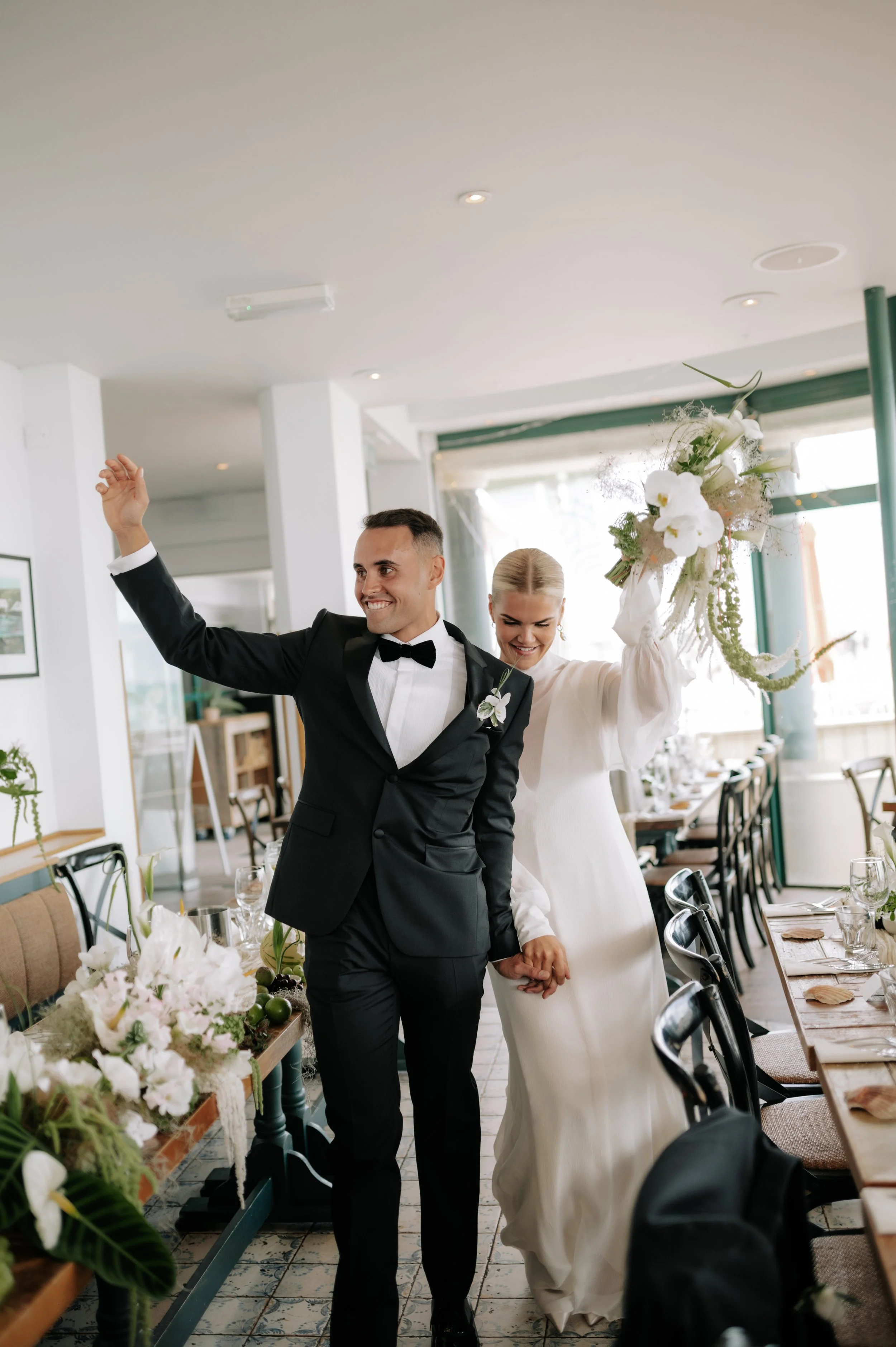 Bride and groom cheer as they enter their wedding reception at Brighton wedding. Fine art documentary wedding photography. 