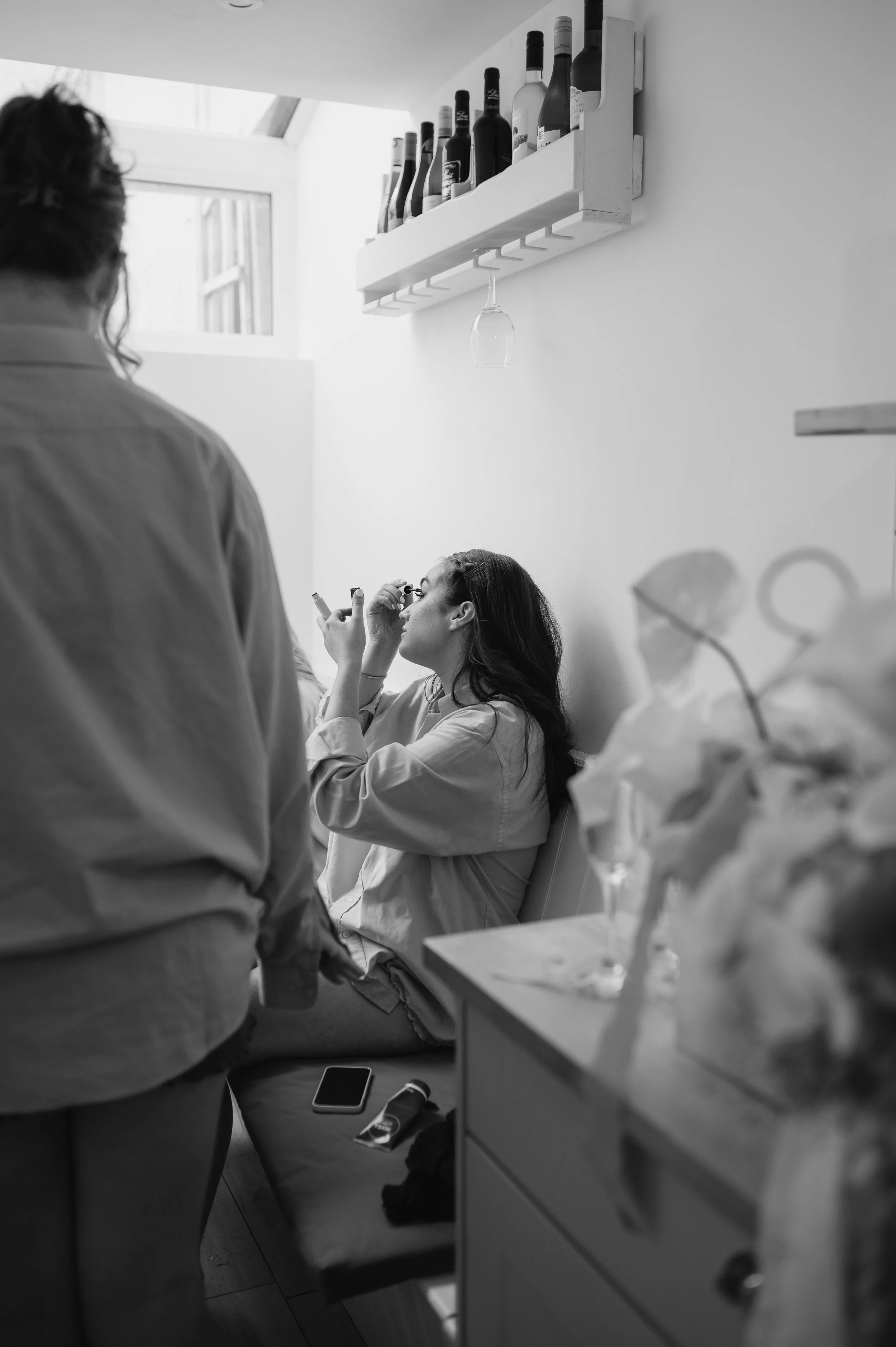 Bridesmaid putting on makeup at Brighton wedding. Fine art documentary wedding photography. 