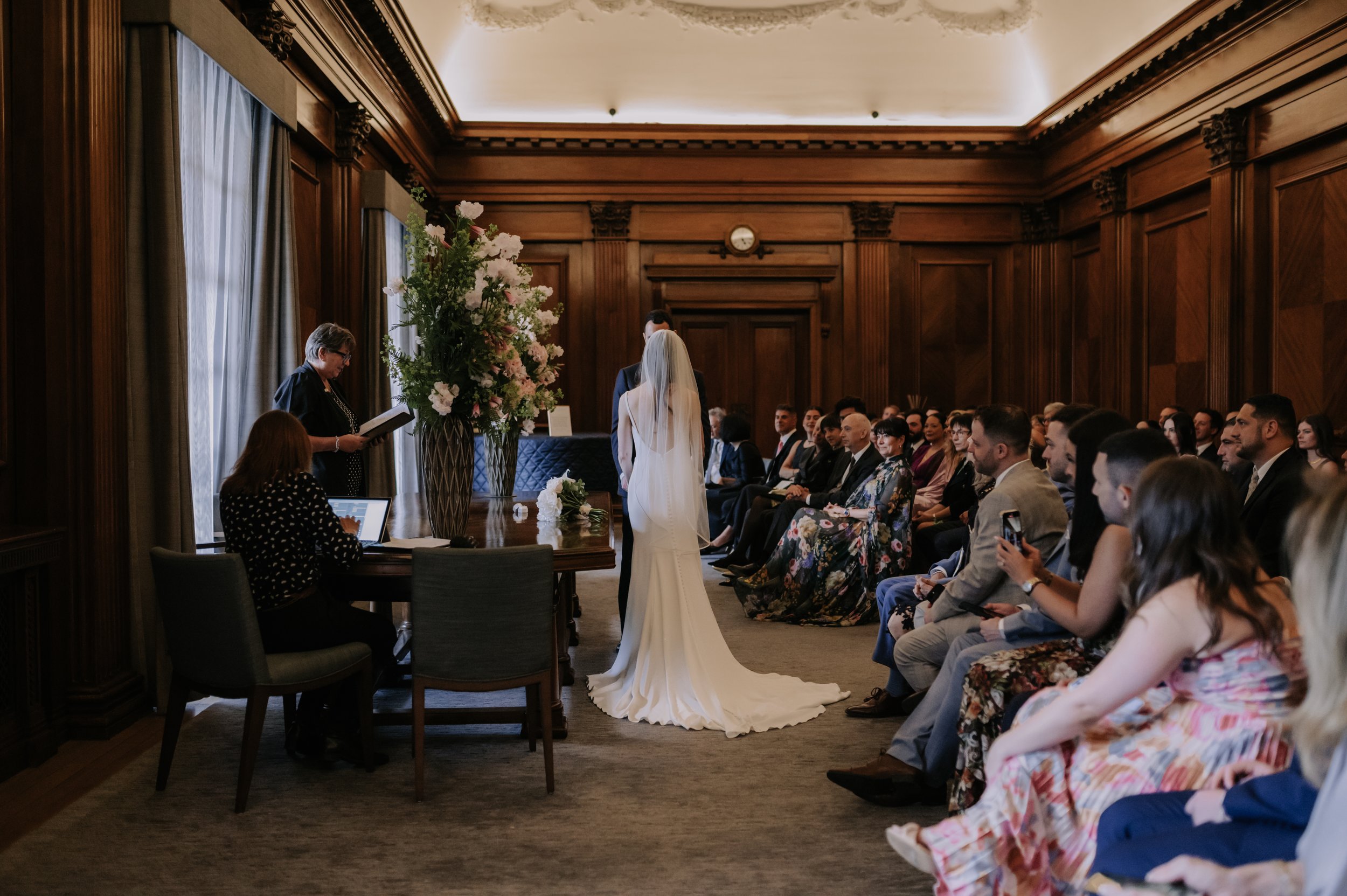 London wedding photography at Marylebone Town Hall back of brides dress and guests 