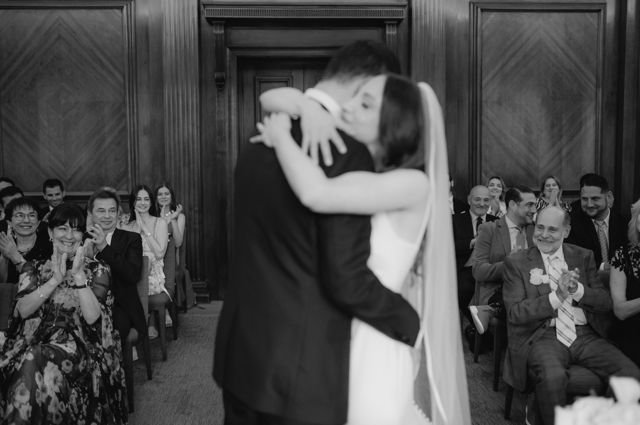 London wedding photography at Marylebone Town Hall bride and groom hugging and guests clapping behind