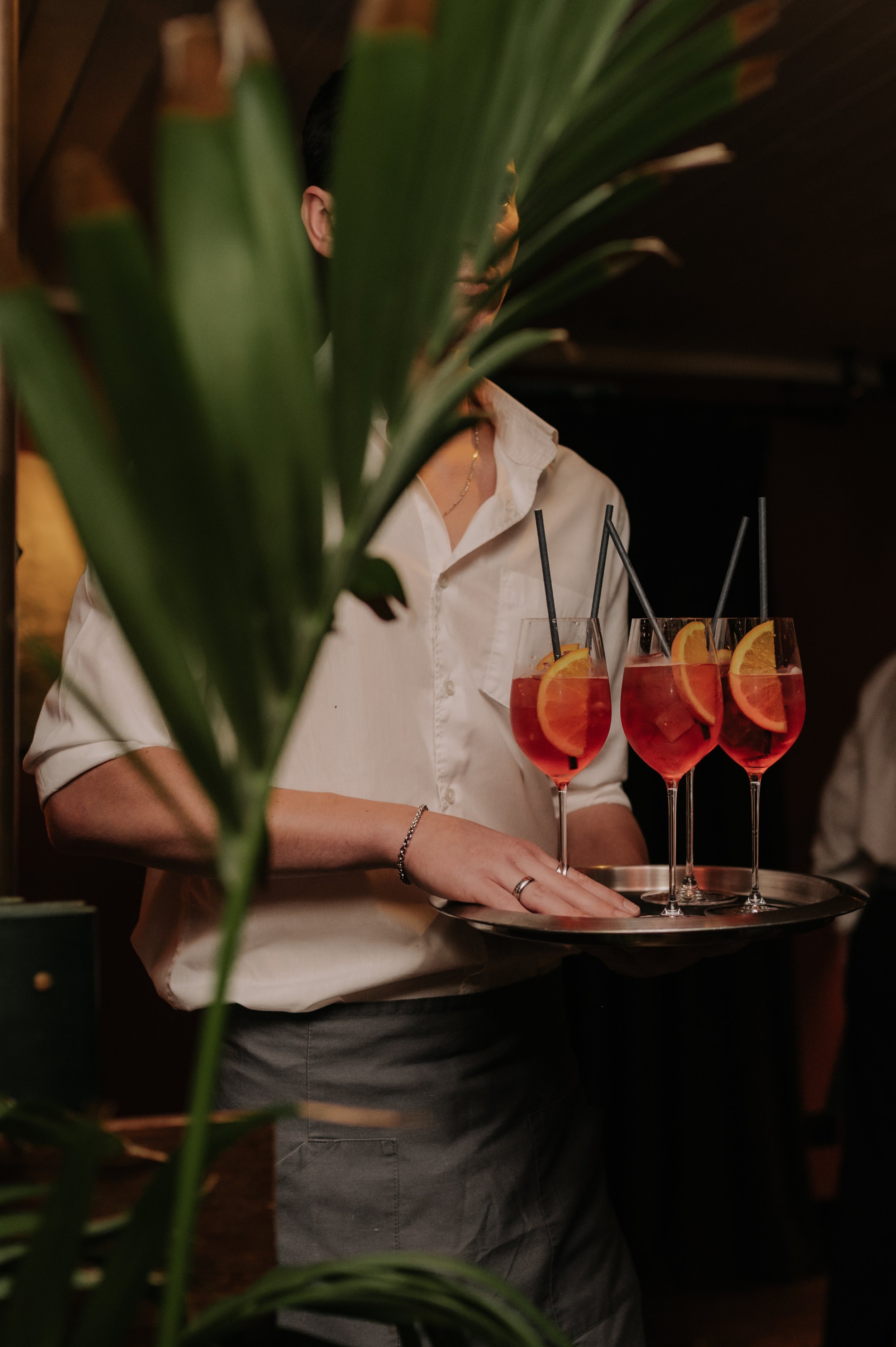 London wedding photography at Belvedere in Holland Park waiter carrying tray of Aperol spritz's