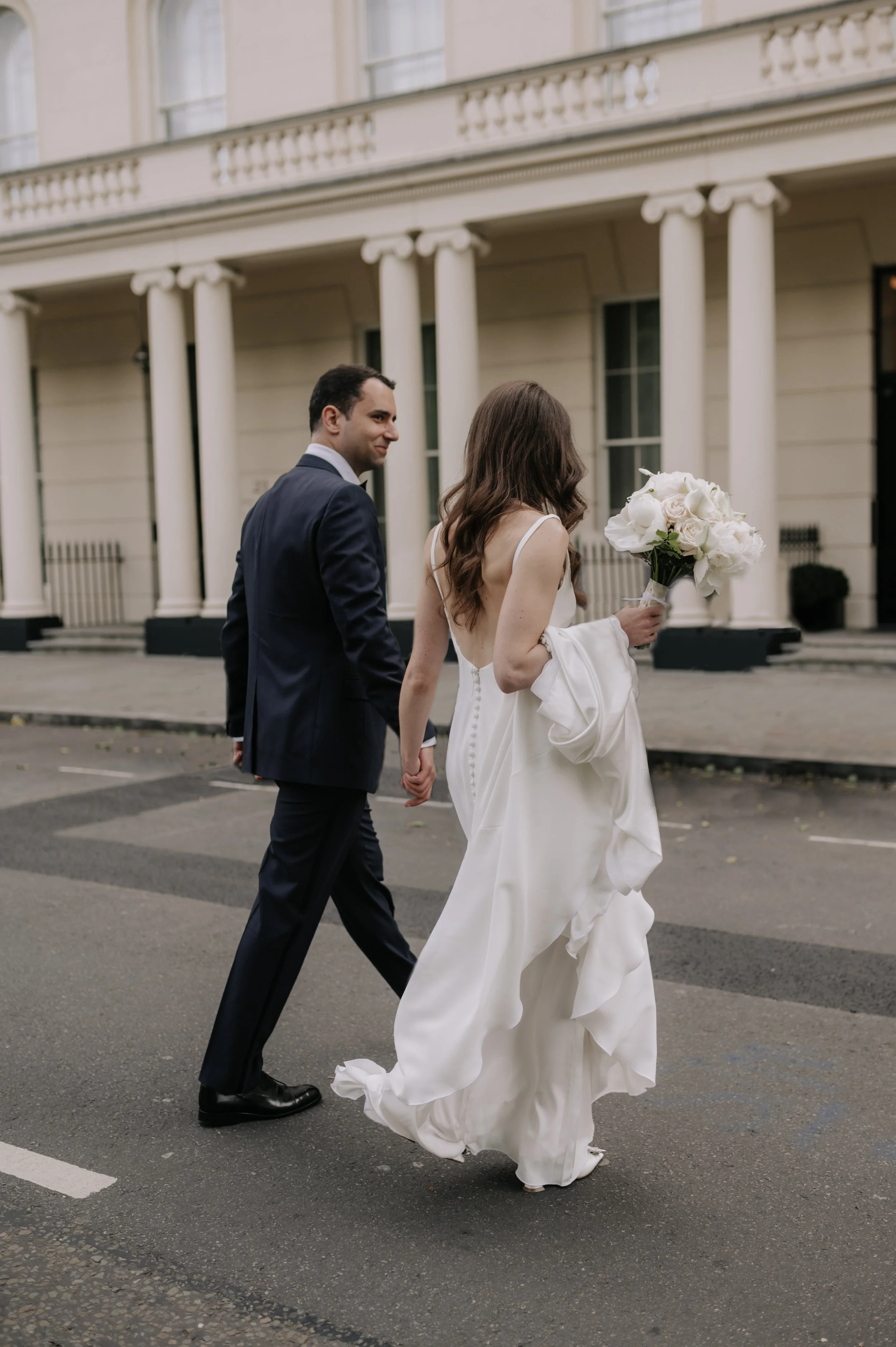 London wedding photography at Marylebone Town Hall bride and groom walking across road holding hands