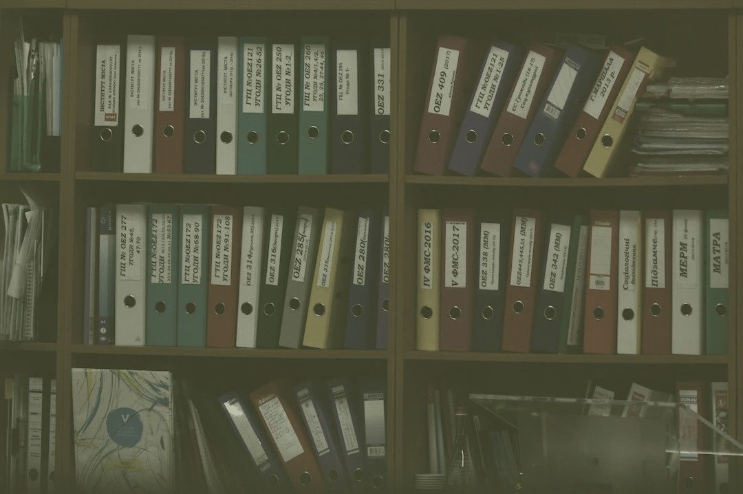 Bookshelf of labeled binders organizing years of program records