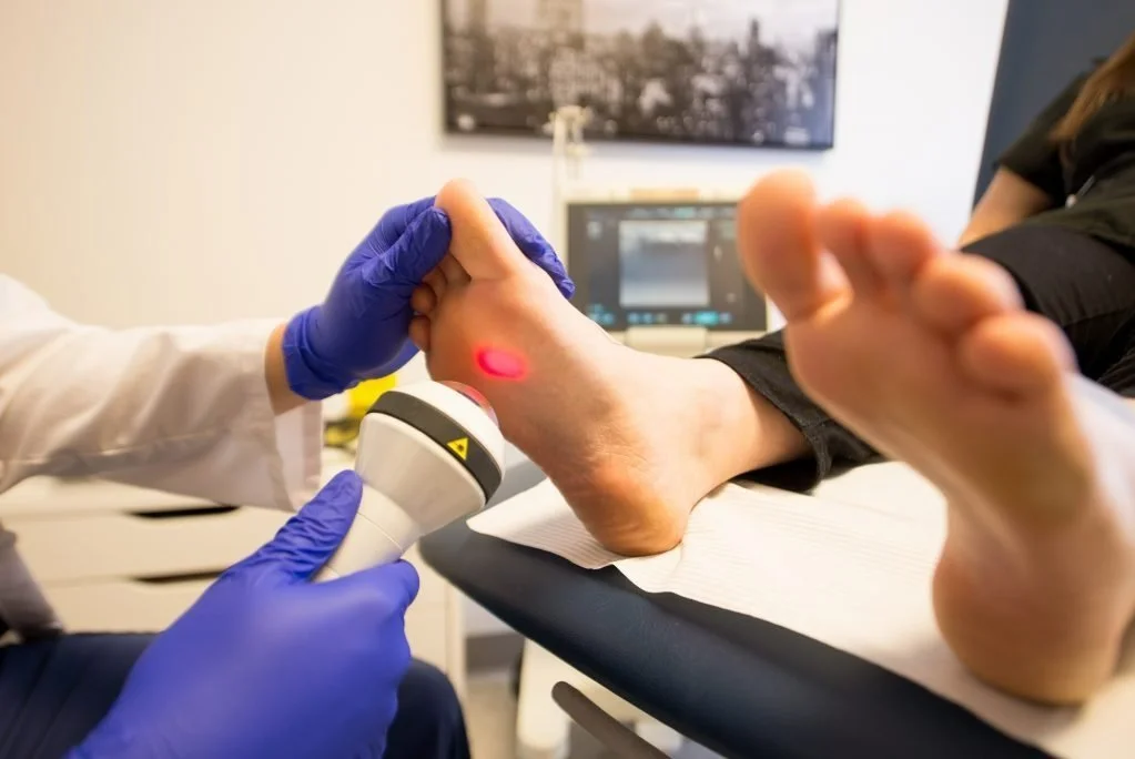 Un professionnel de la santé effectuant une procédure de laser sur le talon d'un patient dans un cabinet médical.