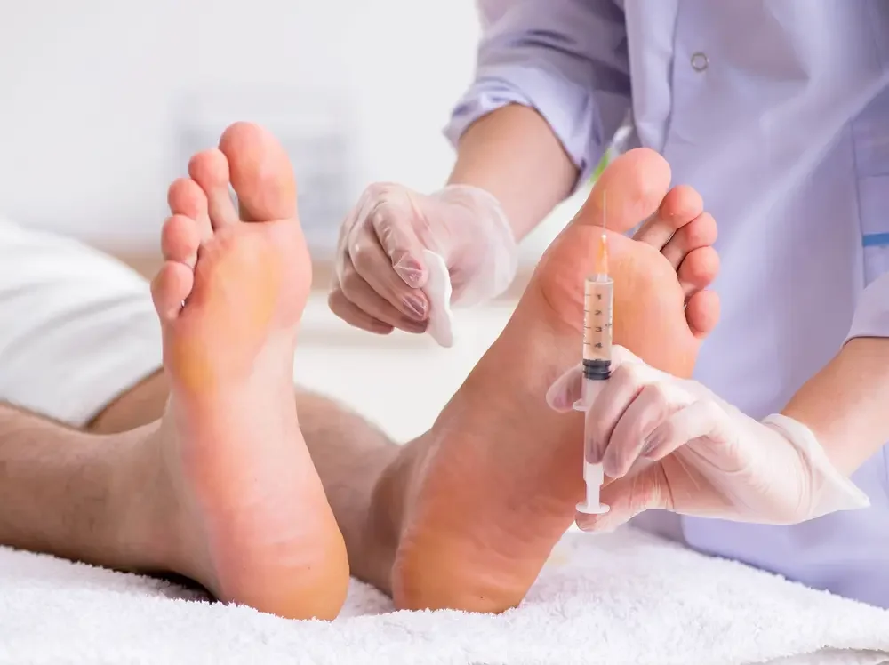Un professionnel médical administrant une injection sous la peau du pied d'un patient