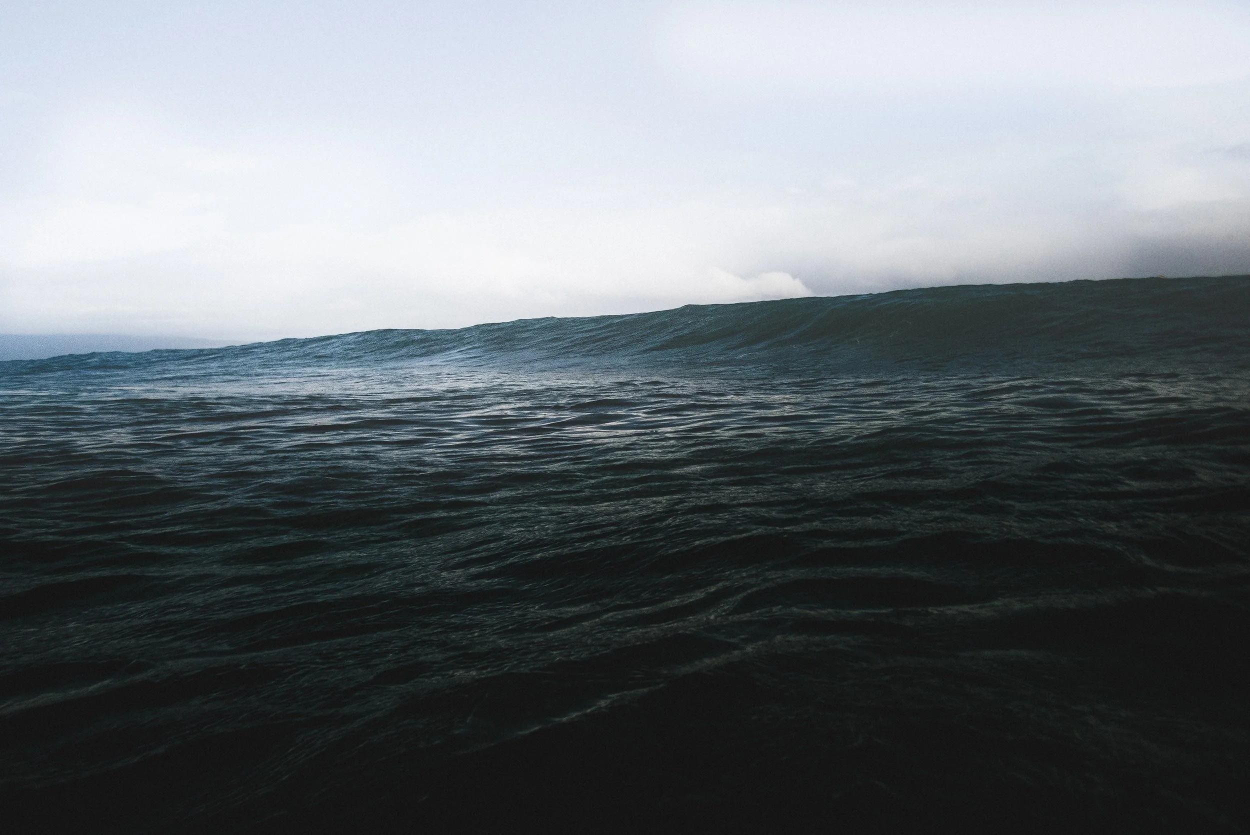 Ocean waves under an overcast sky.