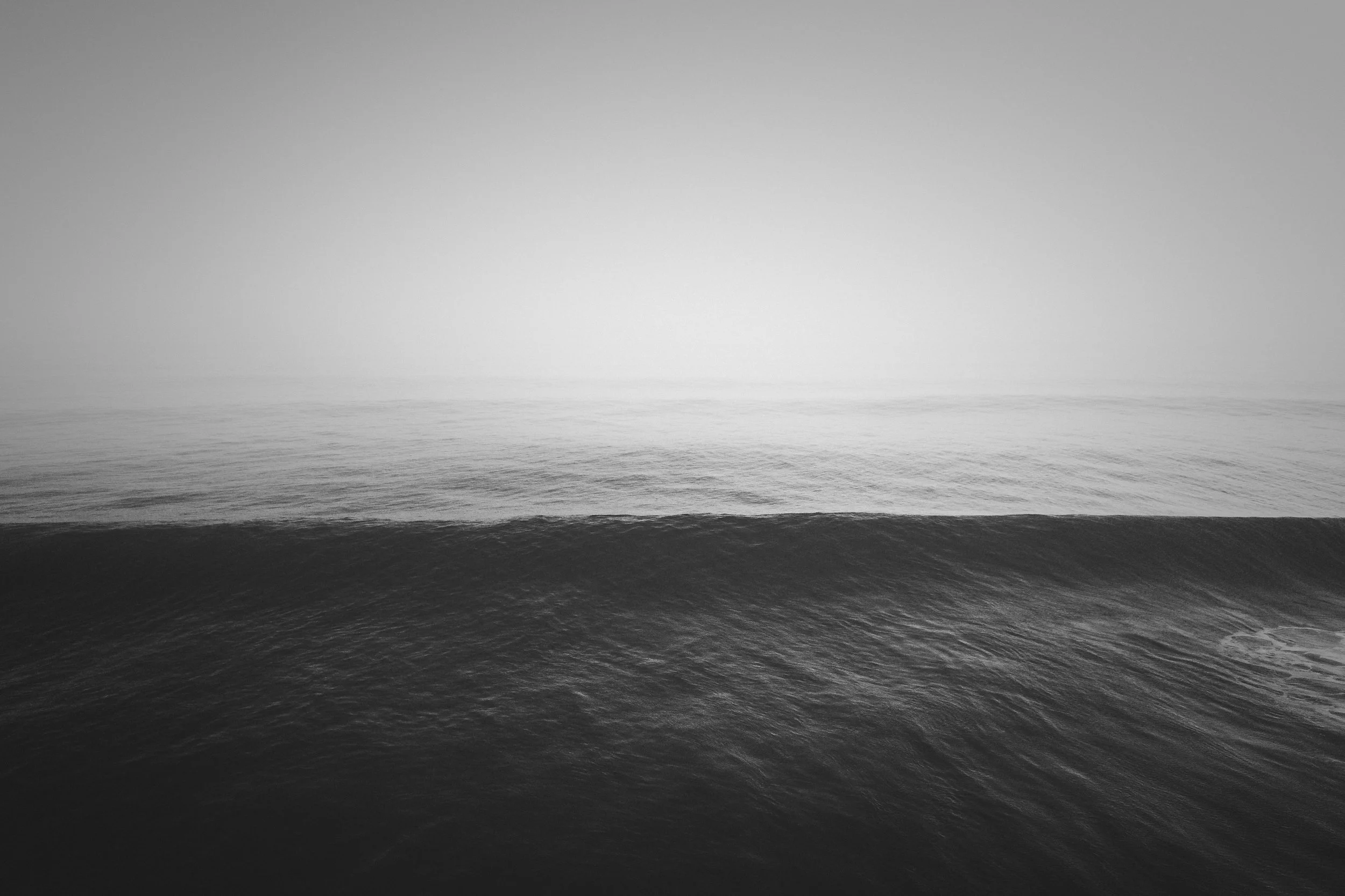 A calm ocean under a cloudy, overcast sky, with no visible land or objects.