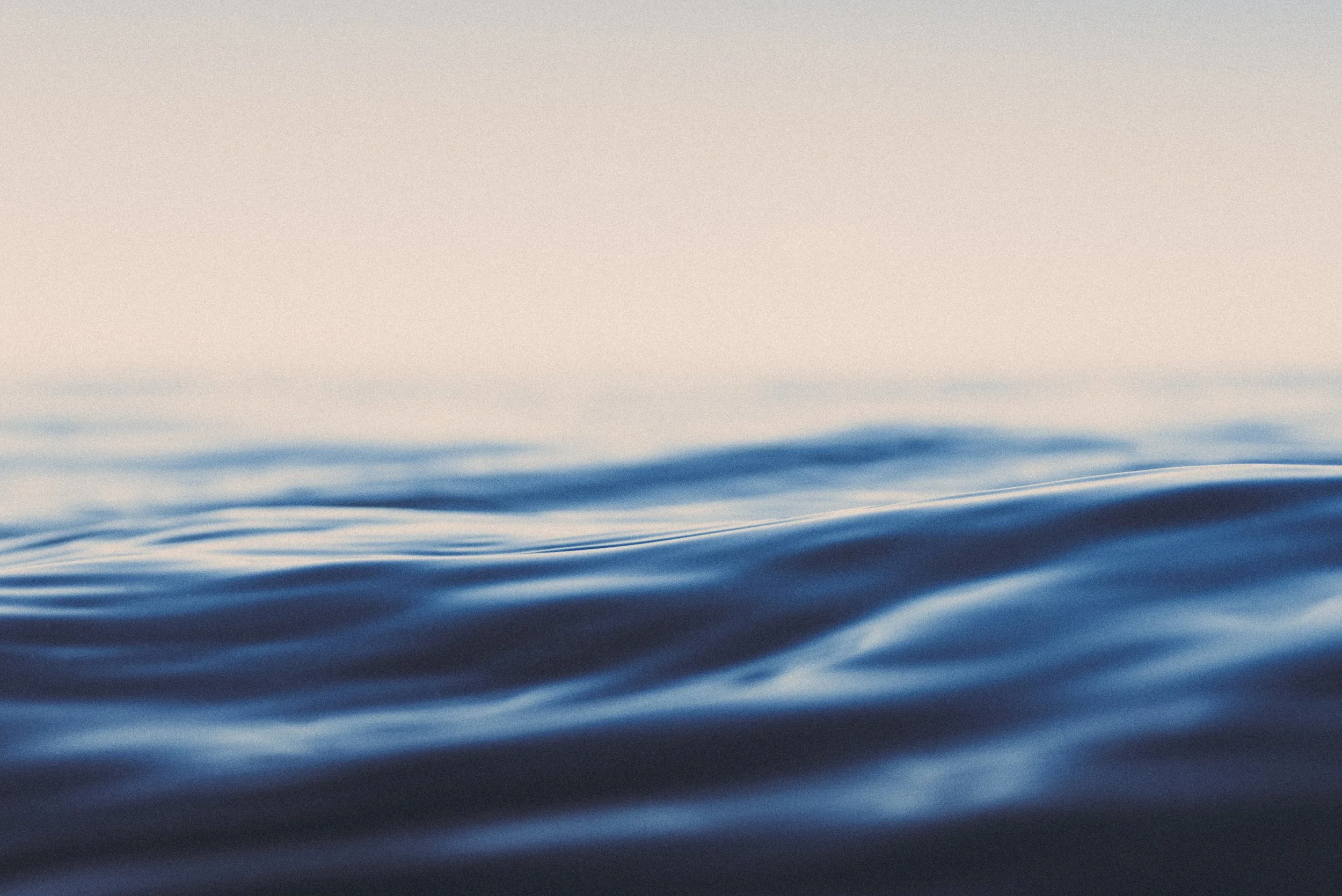 Close-up of calm ocean water with gentle ripples, under a clear sky.