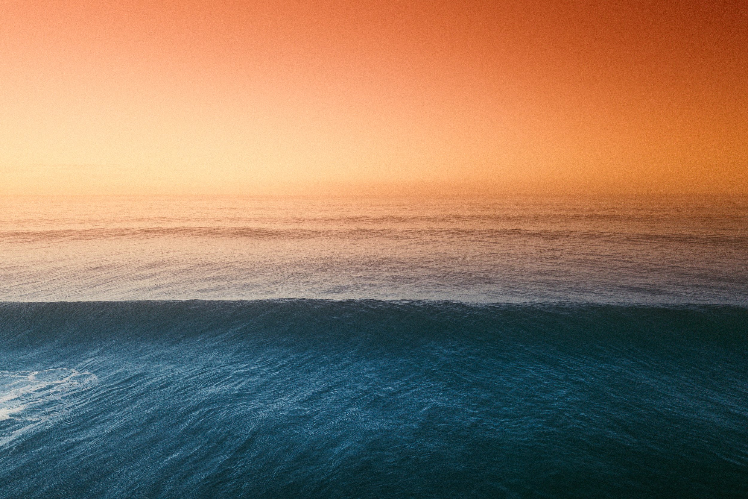 Ocean waves with a clear gradient sky from blue at the horizon to a warm orange hue at the top.