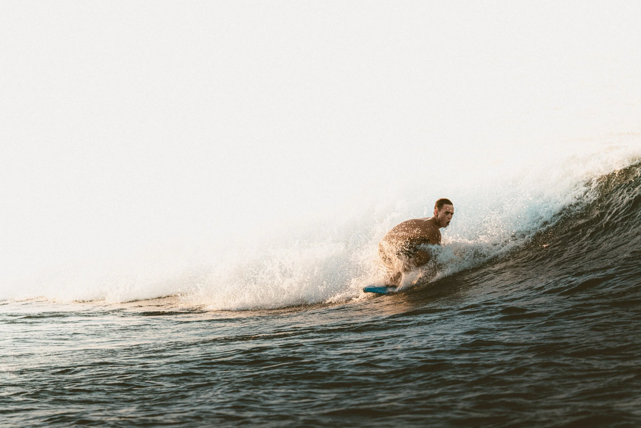 A shirtless man surfing on a wave in the ocean during daylight.