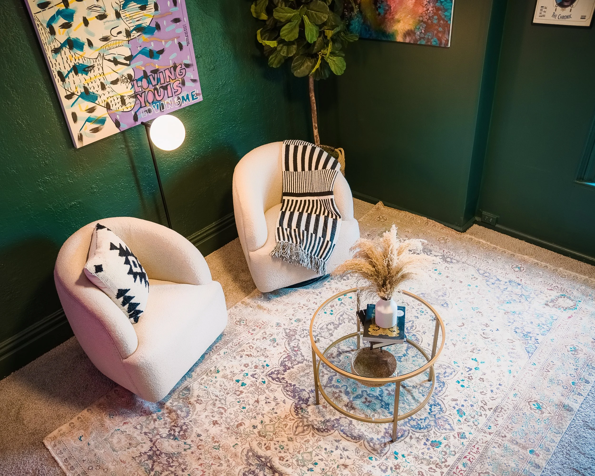 modern living room interior design featuring cream arm chairs with dark green walls and art on walls