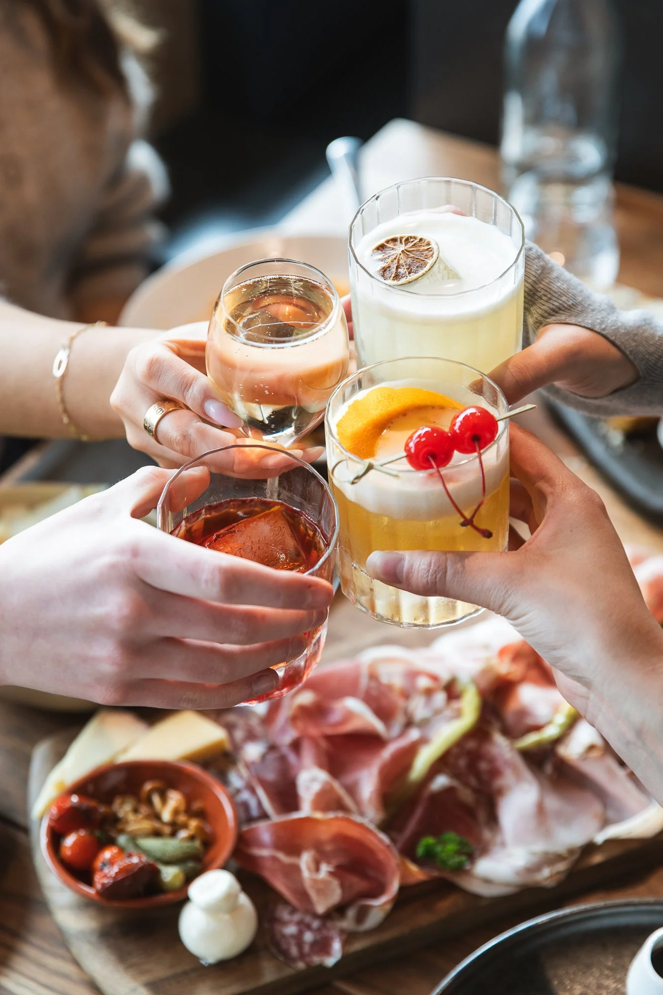 Four people clinking glasses of Mornington Peninsula wine and delicious cocktails over seasonal menu in a casual dining setting just off Main Street, Mornington.