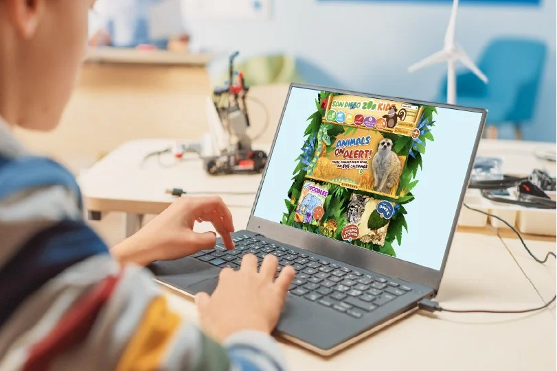 The San Diego Zoo's kids' website visible on a laptop.