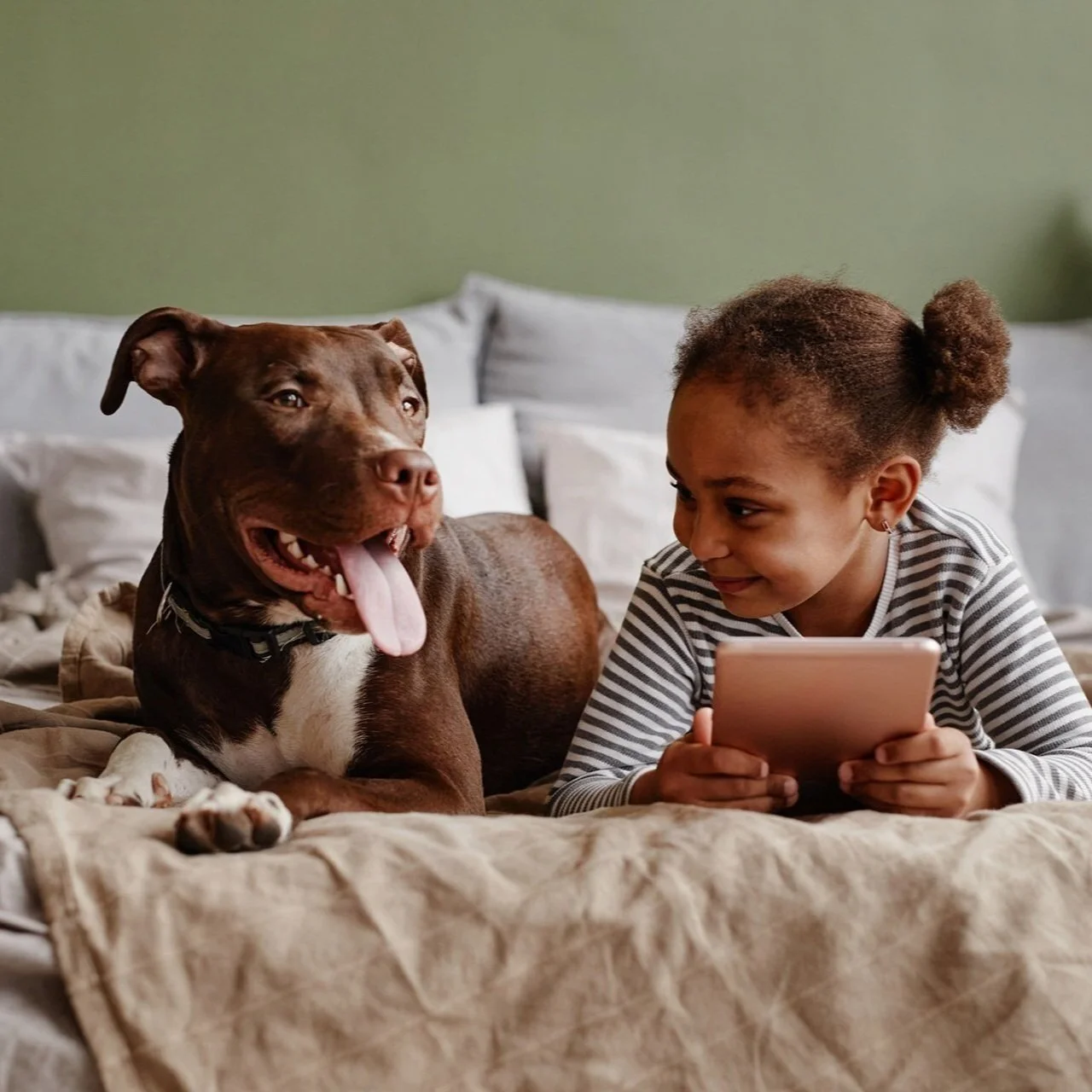 A female child smiling fondly at her dog.