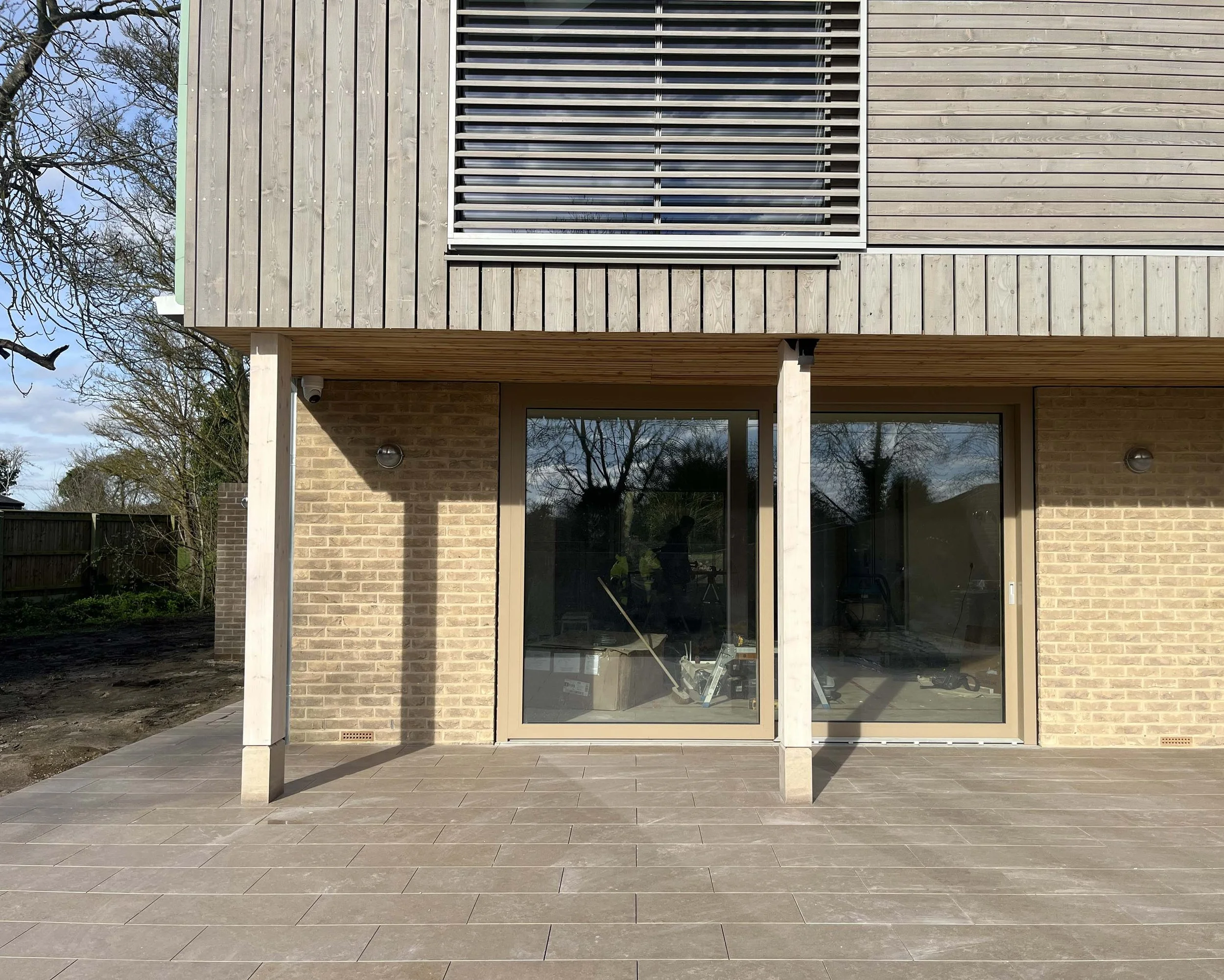 Hereward House – Timber-clad courtyard elevation with brick detailing and large glazed openings in Aldreth, Ely, Cambridgeshire