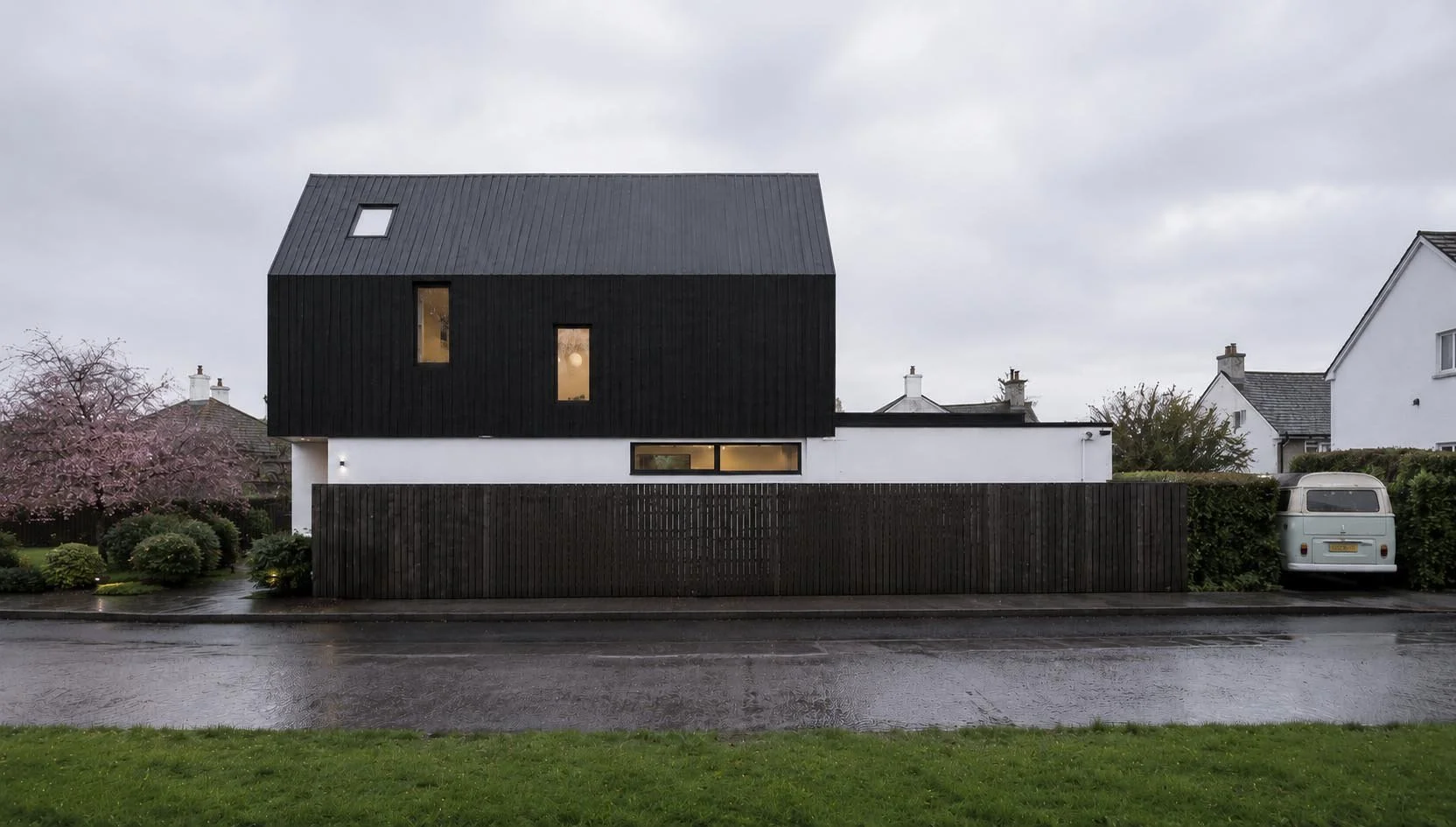 Half House – Side elevation of contemporary new-build house in Cambridge with black timber cladding and simple pitched roof form by Fen Studio Architects
