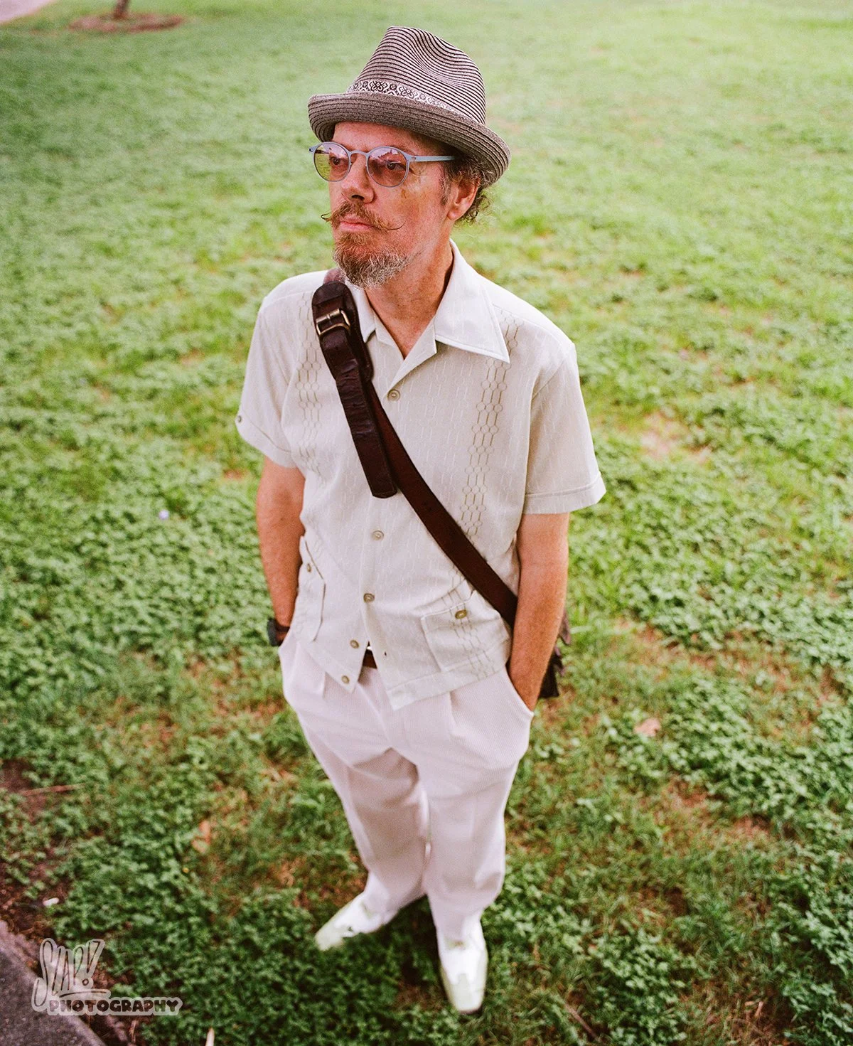 Suavely dressed gentleman standing confidently on grass