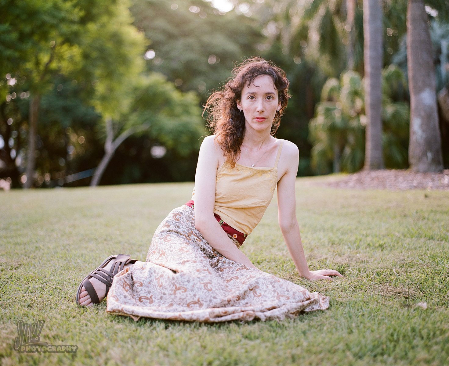 Pretty young lady reclining on grass on a sunny day