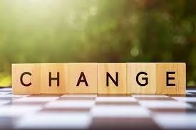 Wooden tiles spelling the word 'CHANGE' on a chessboard with a blurred nature background.