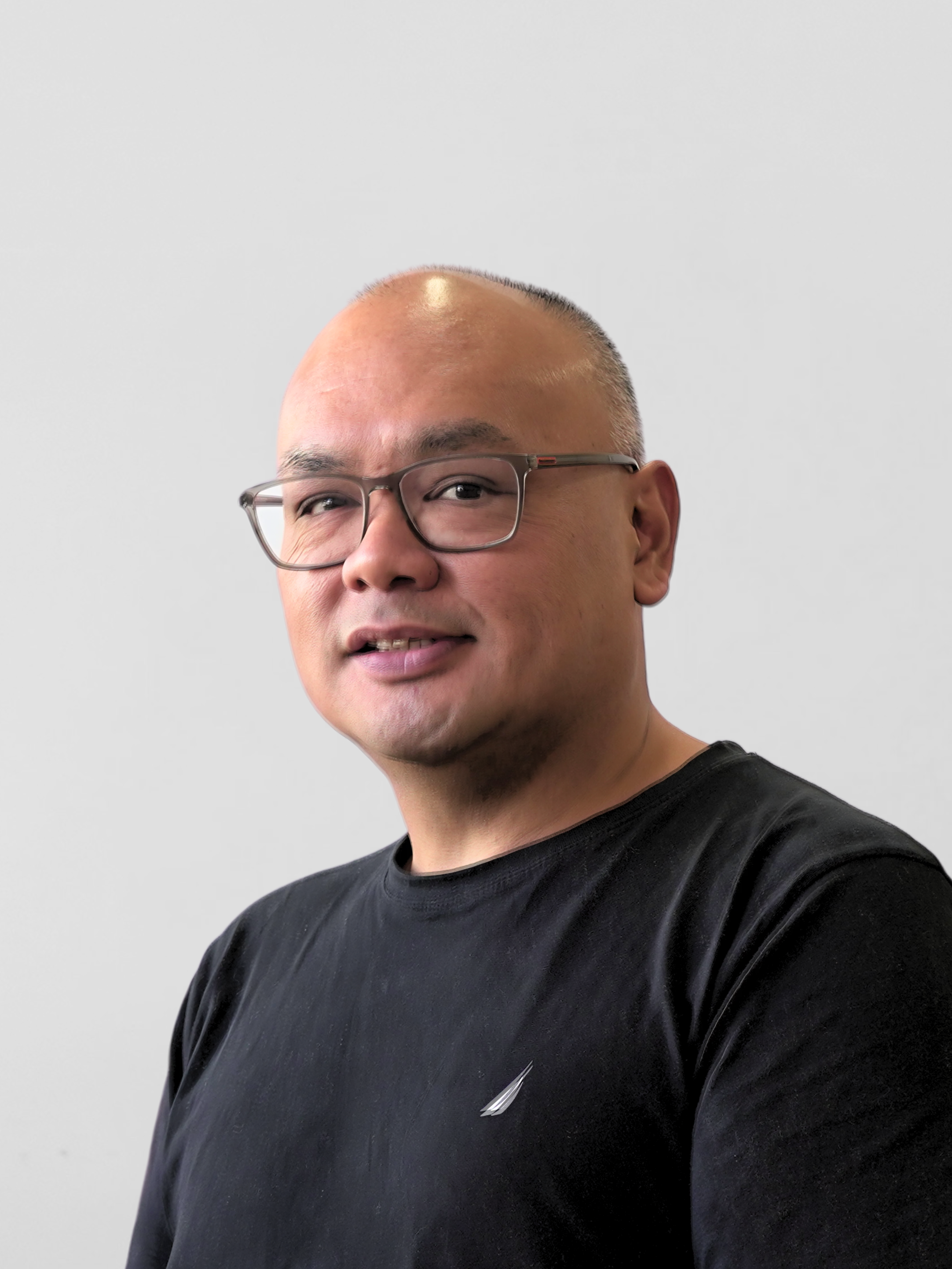 Person wearing a black t-shirt and glasses against a plain background.
