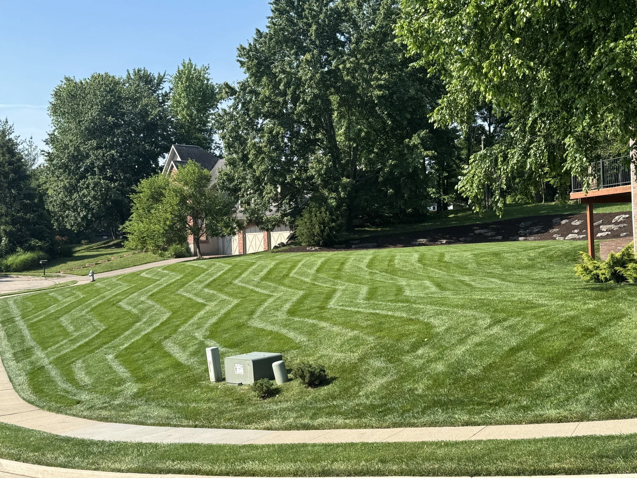 Large lawn with crisp diagonal mowing stripes and a curved walkway