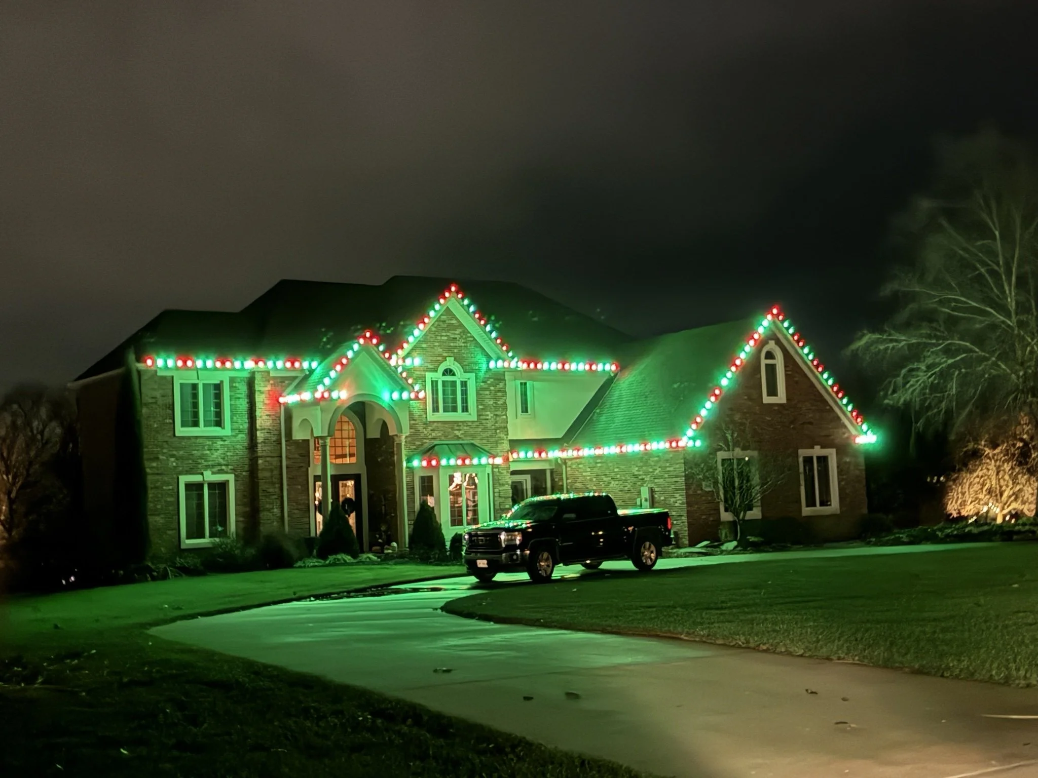 Home at night with green and red Christmas lights outlining the roofline