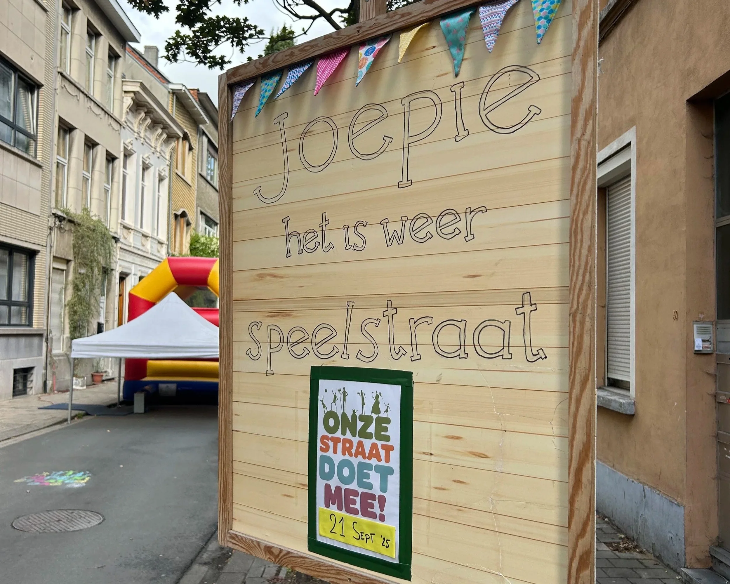 Bord met tekst in het Nederlands dat zegt "Jope, het is weer speelstraat", met een poster onderaan die reclameert voor een evenement op 21 september.