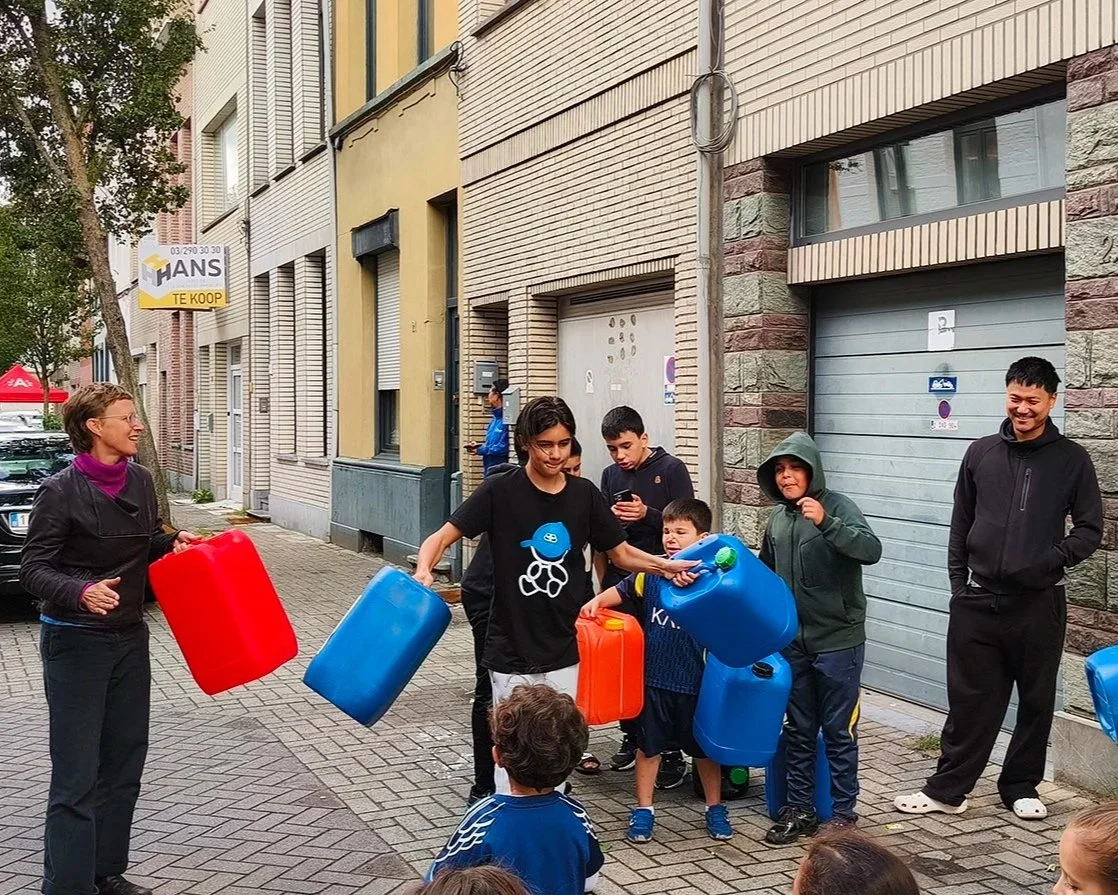 Mensen spelen een waterspel waarbij ze plastic jerrycans gebruiken als onderdeel van het spel op straat.