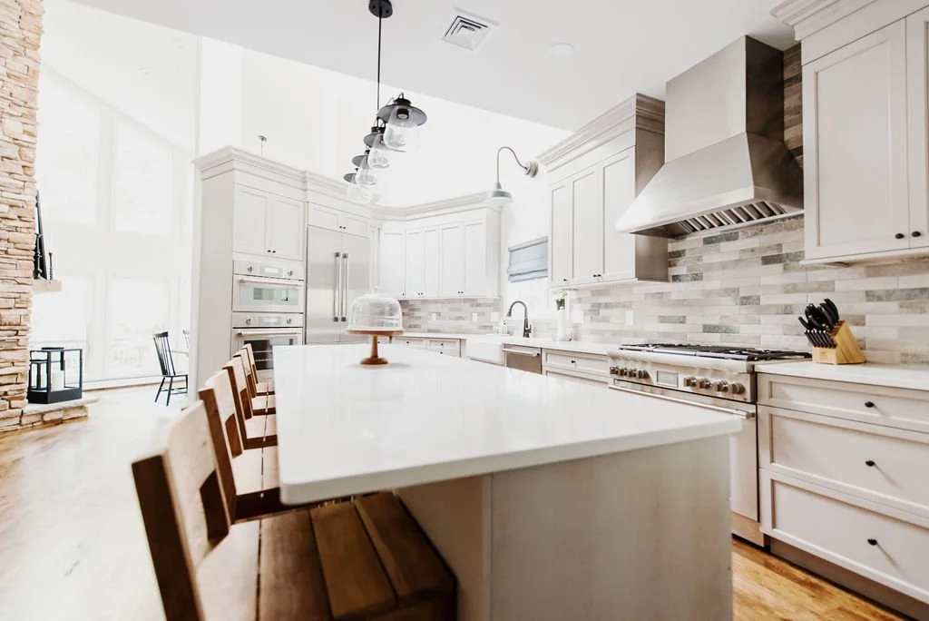 Custom kitchen with white cabinetry, stainless steel range hood and tile backsplash designed by FD Design Co.